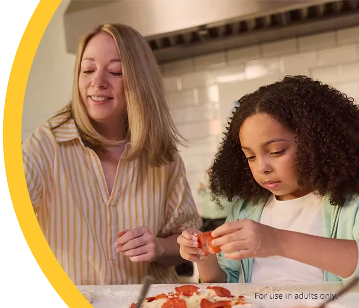 A mother and daughter making pizza in a kitchen